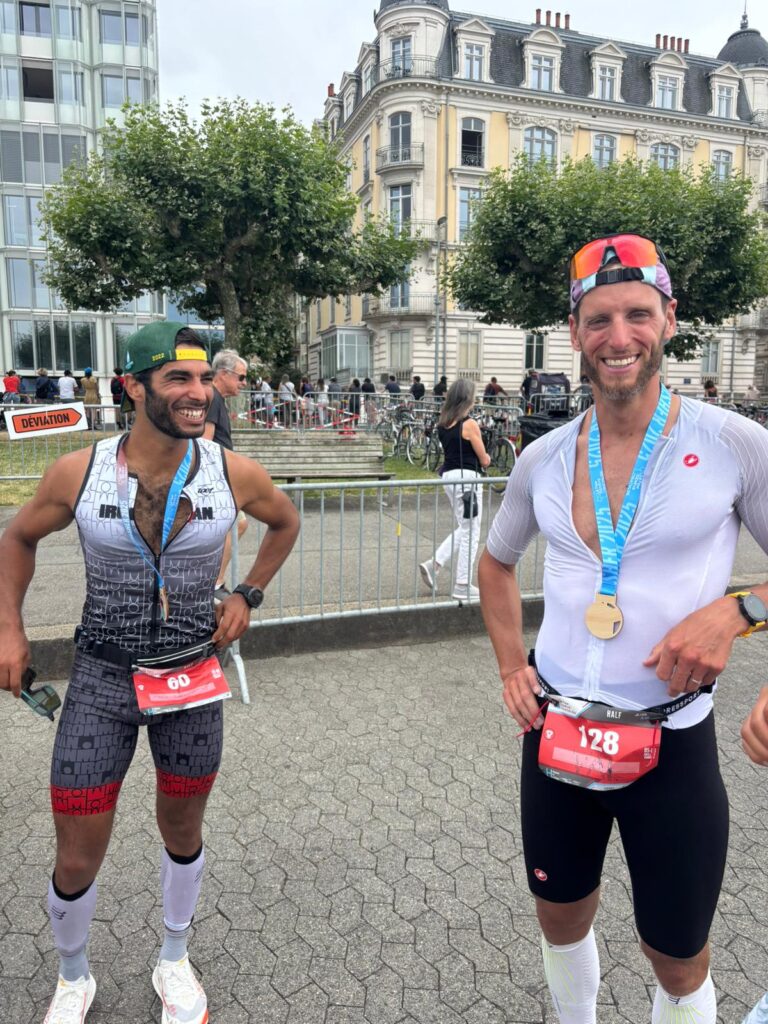 Deux hommes après l’arrivée d’un triathlon à Genève, finishers souriants après leur première course.